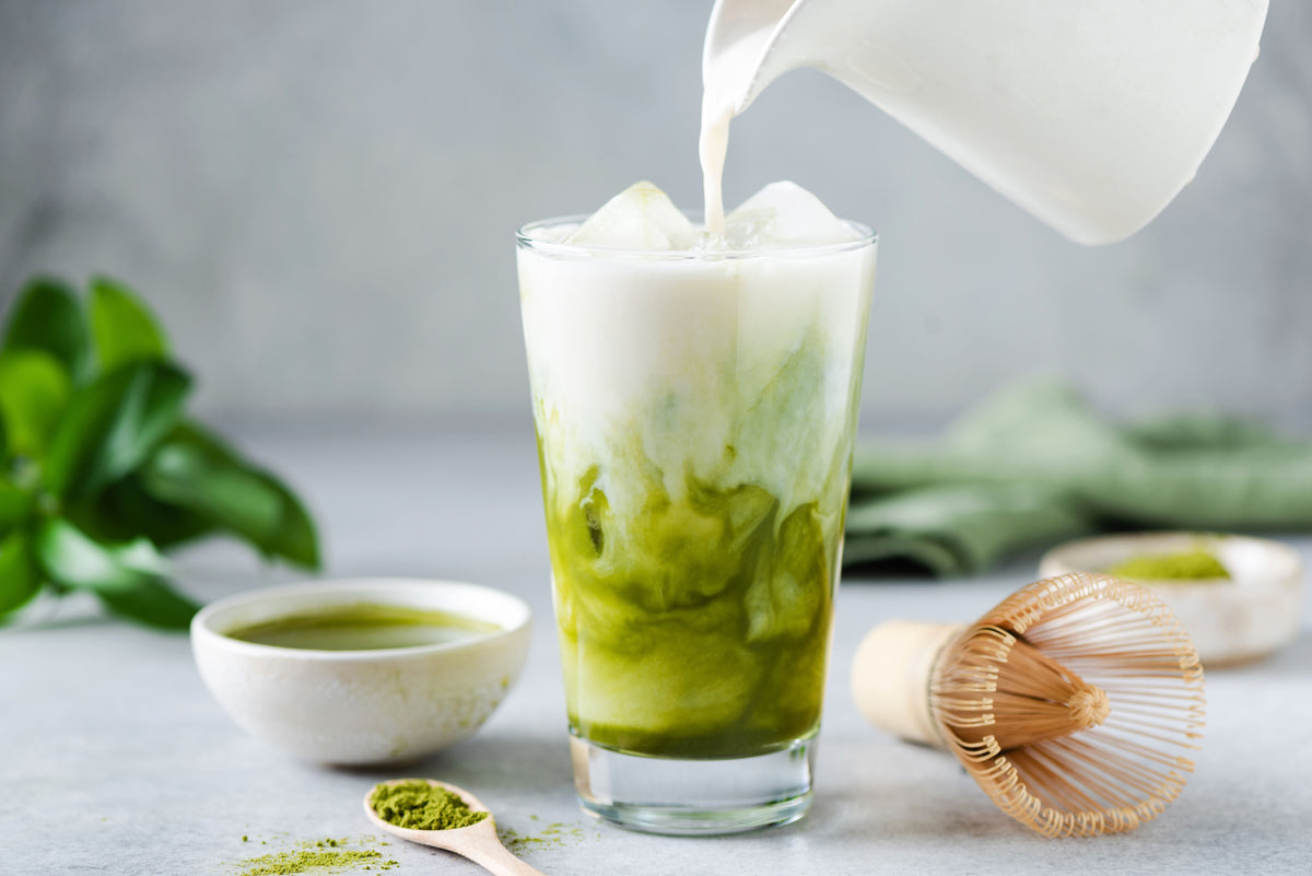 Matcha Latte Zubereitung mit aufgeschäumter Milch und Matcha Pulver