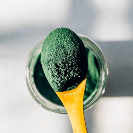 Bio Spirulina Hawaii Pulver neben frischem Gemüse – Symbol für Gesundheit und Energie