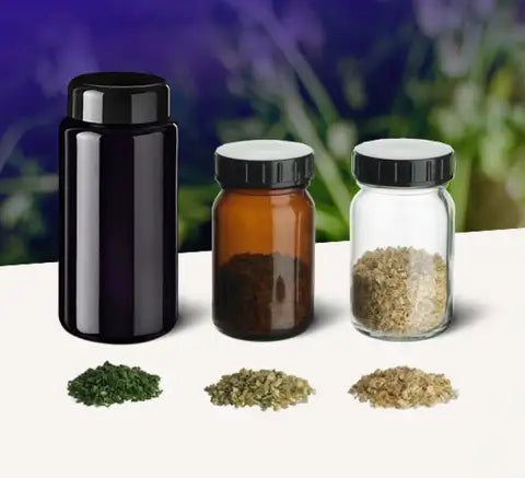 Bernsteinfarbenes Glasgefäß mit schwarzem Deckel, enthaltend getrocknete Kräuter.